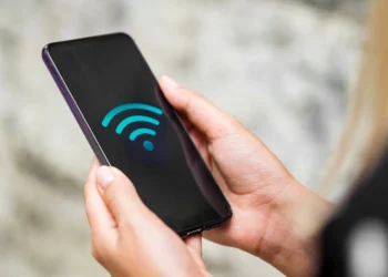 Pessoa segurando um smartphone exibindo o símbolo de Wi-Fi, representando a conectividade sem fio