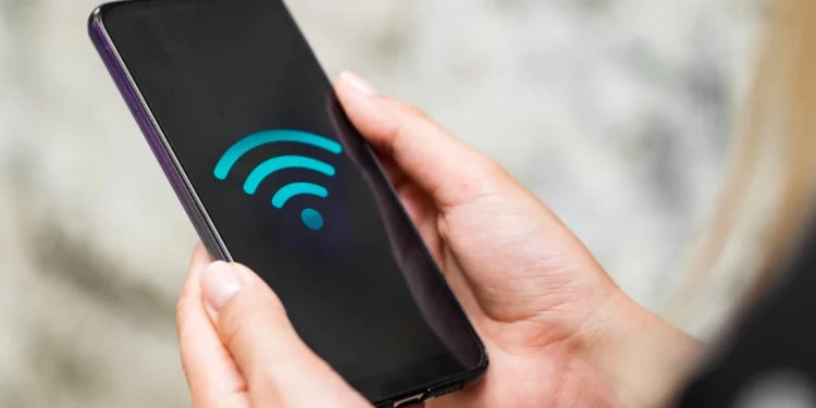 Pessoa segurando um smartphone exibindo o símbolo de Wi-Fi, representando a conectividade sem fio