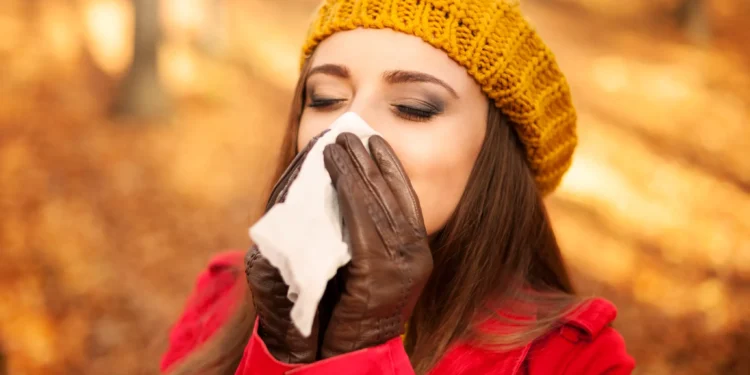 Mulher espirrando e usando lenço em um dia de outono