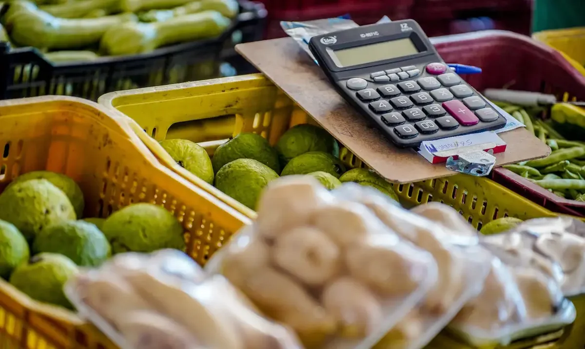 Frutas frescas e uma calculadora em cima de uma caixa de mercado.