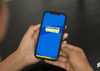 Pessoa segurando um celular com a tela do Cadastro Único aberta, representando a consulta ao NIS.