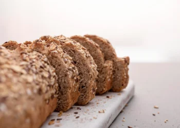 Fatias de pão caseiro com aveia sobre uma tábua de corte.