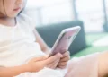 Criança segurando um smartphone, ilustrando o uso de dispositivos móveis por crianças