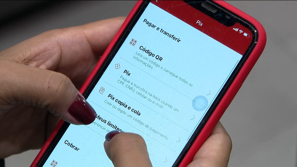 Pessoa utilizando o aplicativo Pix no celular, acessando opções de pagamento e transferências. Alerta para o golpe do Pix errado. 