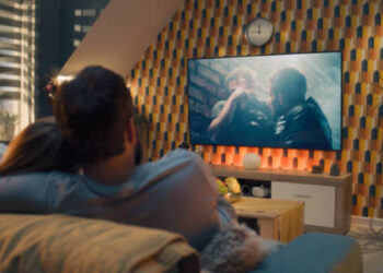 Casal assistindo uma cena emocionante de série turca em TV grande no sofá.